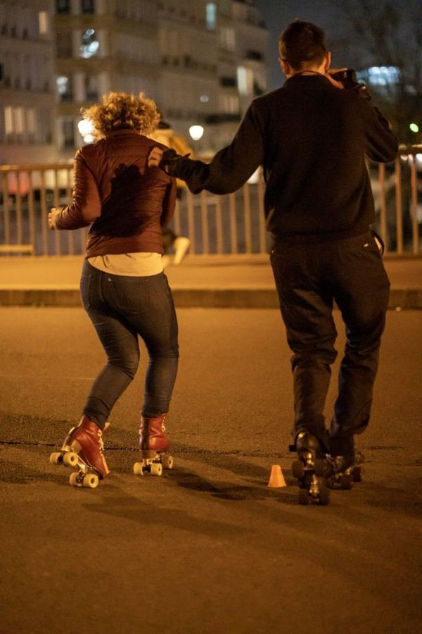 Roller skaters dancing on a Paris street at night