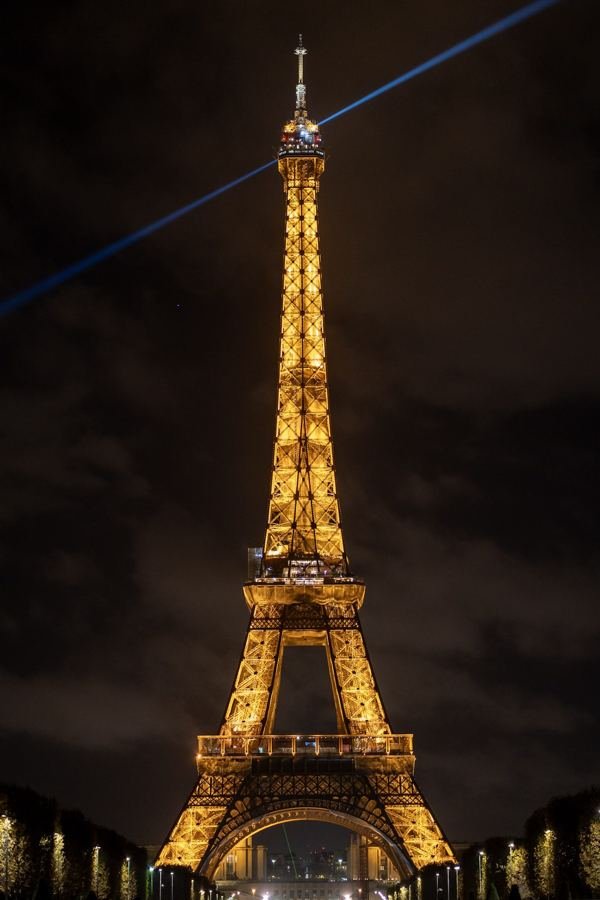 The illuminated Eiffel Tower at night with a searchlight beam